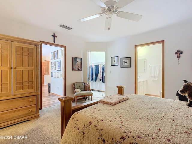 carpeted bedroom with ensuite bath, a spacious closet, a closet, and ceiling fan