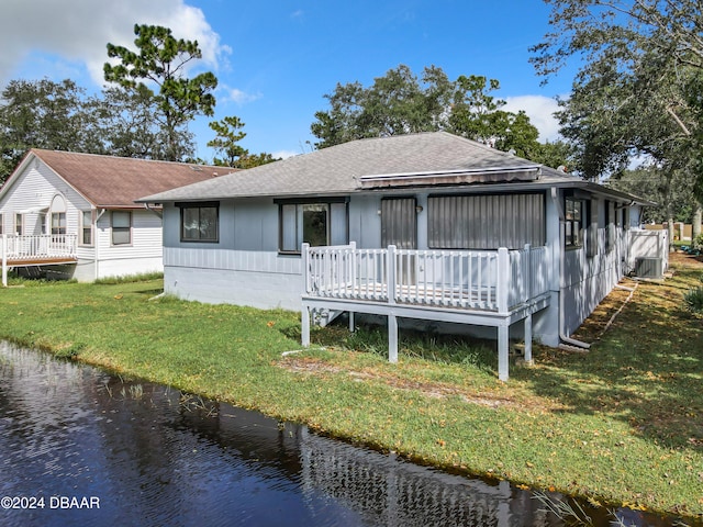 rear view of property with a lawn and a deck with water view