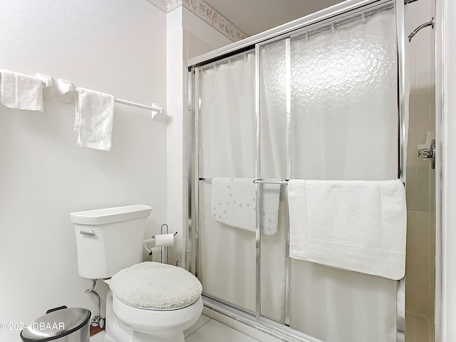 bathroom featuring tile patterned floors, a shower with shower door, and toilet