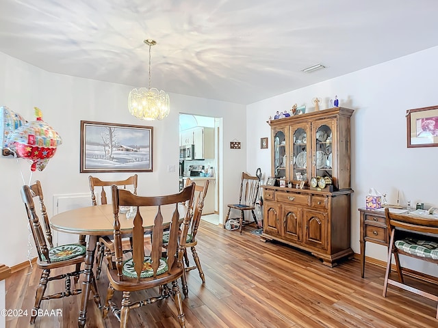 dining area with hardwood / wood-style floors and a notable chandelier