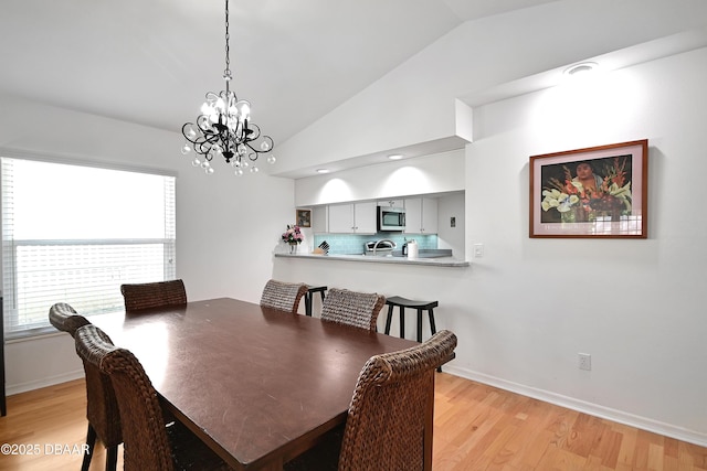 dining area featuring vaulted ceiling, a chandelier, and light wood-type flooring