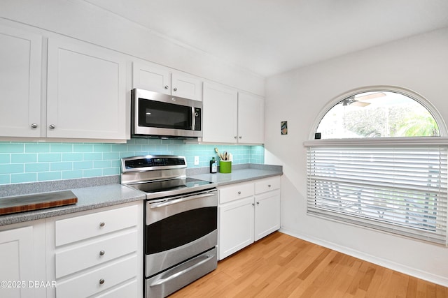 kitchen with stainless steel appliances, white cabinetry, tasteful backsplash, and light wood-type flooring