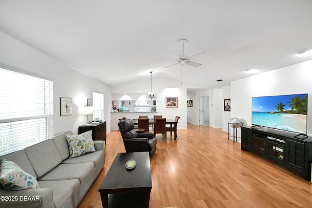 living room with lofted ceiling, ceiling fan with notable chandelier, and light hardwood / wood-style flooring