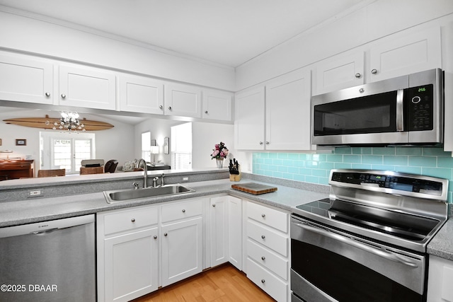 kitchen with stainless steel appliances, white cabinetry, sink, and tasteful backsplash