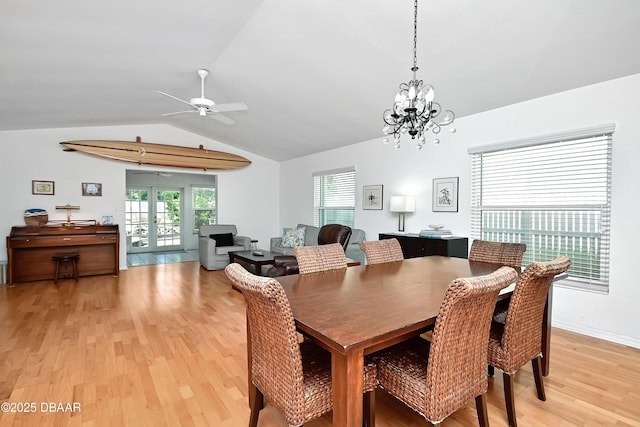 dining space with lofted ceiling, ceiling fan with notable chandelier, light hardwood / wood-style floors, and french doors