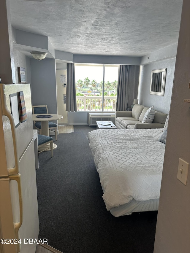 2700 N Atlantic Ave Unit 423, Daytona Beach, FL 32118 - carpeted bedroom with a textured ceiling, freestanding refrigerator, and a wall mounted air conditioner