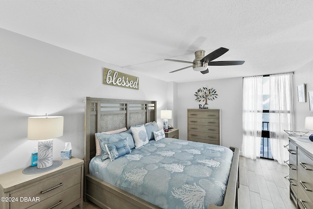 bedroom featuring ceiling fan, light wood-type flooring, and a textured ceiling