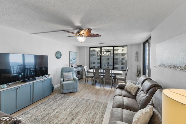 living room with ceiling fan, light hardwood / wood-style floors, a textured ceiling, and expansive windows