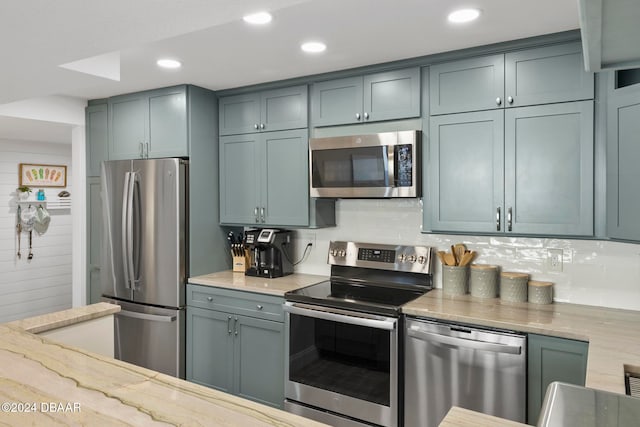 kitchen featuring decorative backsplash, light stone countertops, and appliances with stainless steel finishes