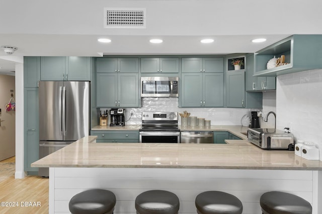 kitchen with kitchen peninsula, light stone counters, a breakfast bar, and stainless steel appliances