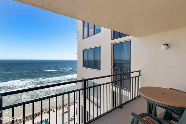 balcony with a water view and a view of the beach