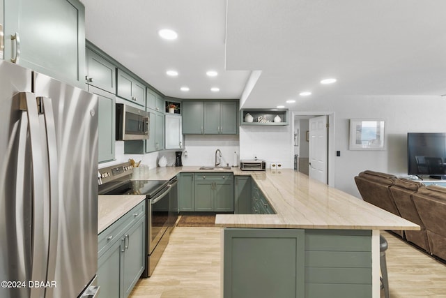 kitchen featuring green cabinets, sink, stainless steel appliances, and light hardwood / wood-style floors