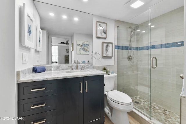 bathroom with vanity, wood-type flooring, ceiling fan, toilet, and a shower with shower door