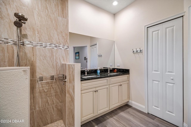 bathroom with hardwood / wood-style flooring, vanity, and tiled shower