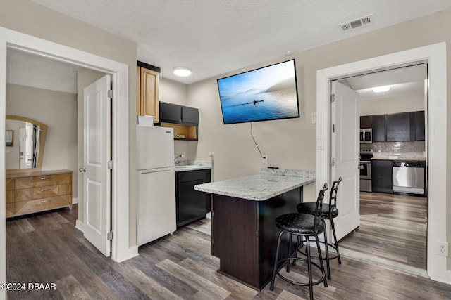 kitchen featuring a kitchen breakfast bar, dark wood-type flooring, stainless steel appliances, and a textured ceiling