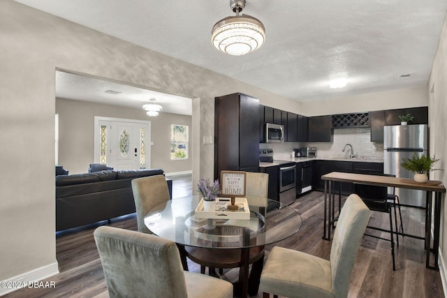 dining room featuring a textured ceiling, sink, a chandelier, and dark hardwood / wood-style floors