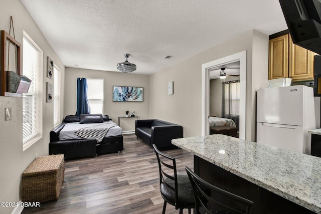 bedroom featuring a textured ceiling, white fridge, and dark hardwood / wood-style floors