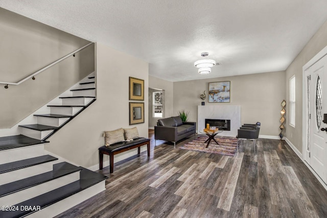 living room with a textured ceiling, dark wood-type flooring, and a high end fireplace