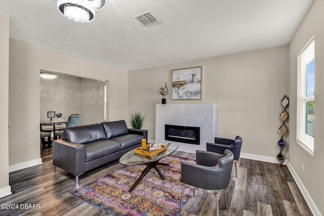 living room featuring a fireplace, plenty of natural light, dark wood-type flooring, and a textured ceiling