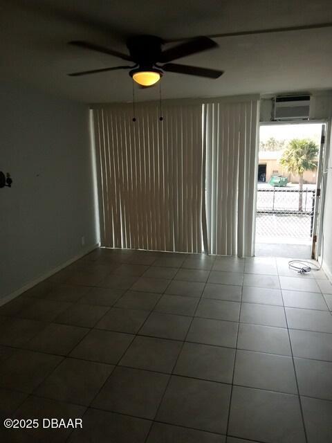 tiled empty room with ceiling fan, a wealth of natural light, and a wall mounted AC