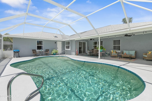 view of pool featuring outdoor lounge area, ceiling fan, a patio area, and glass enclosure