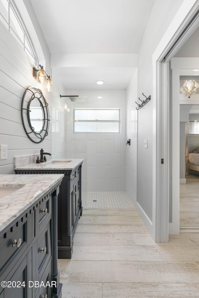 bathroom with wooden walls, vanity, wood-type flooring, and tiled shower