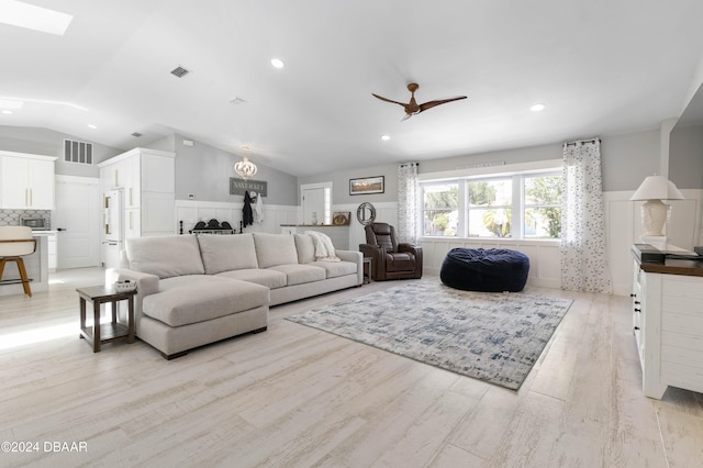 living room with ceiling fan, light wood-type flooring, and lofted ceiling with skylight