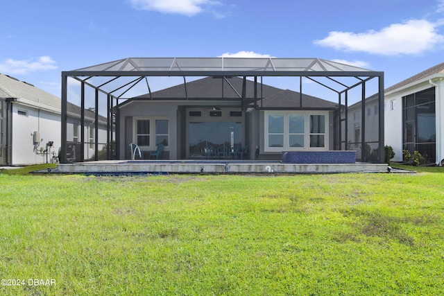 back of property with ceiling fan, a lanai, and a yard