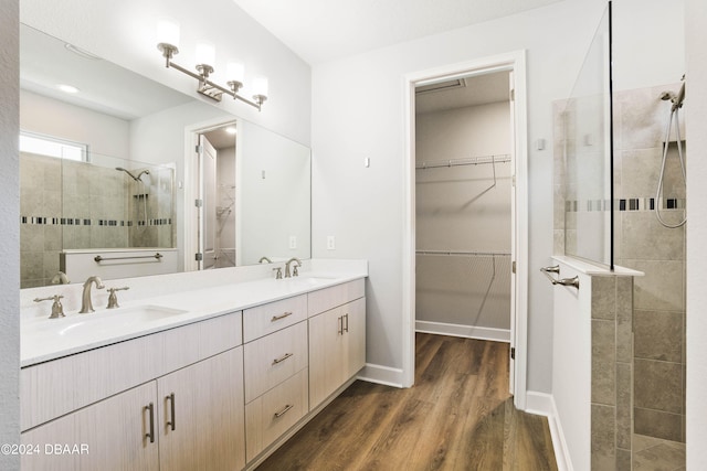 bathroom with hardwood / wood-style flooring, vanity, and a tile shower