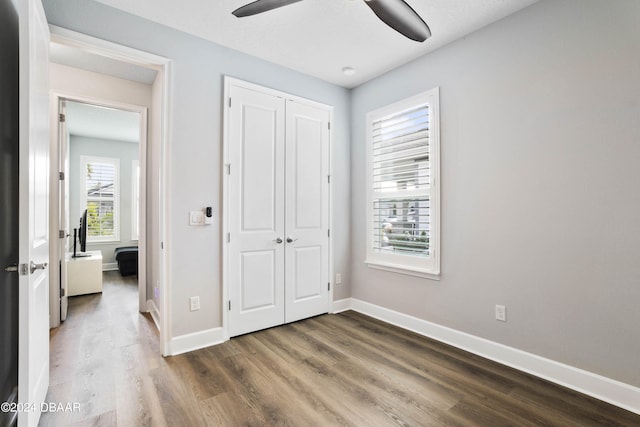 unfurnished bedroom with dark wood-type flooring, a closet, and ceiling fan