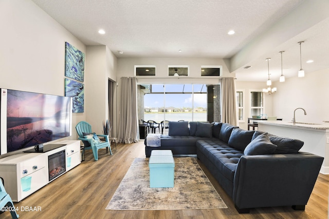 living room with sink, a chandelier, wood-type flooring, and a textured ceiling