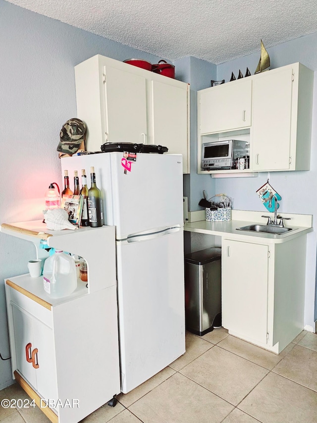 kitchen featuring white cabinets, a textured ceiling, sink, and light tile patterned floors