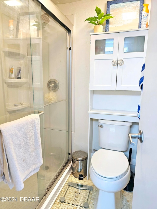 bathroom with a shower with shower door, tile patterned floors, and toilet