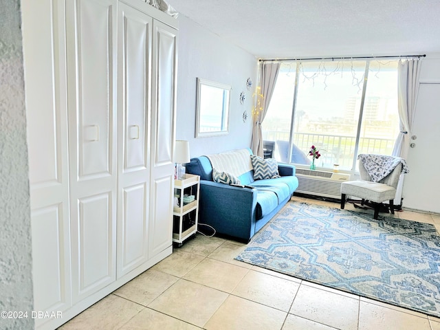 living area featuring a wall unit AC, light tile patterned flooring, and a textured ceiling