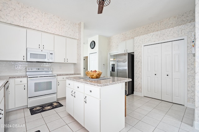 kitchen with white cabinetry, white appliances, light tile patterned flooring, and a center island