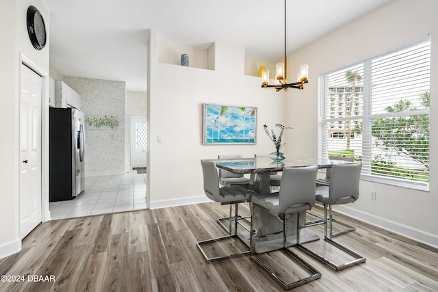 dining area featuring light wood-type flooring, a notable chandelier, and a healthy amount of sunlight