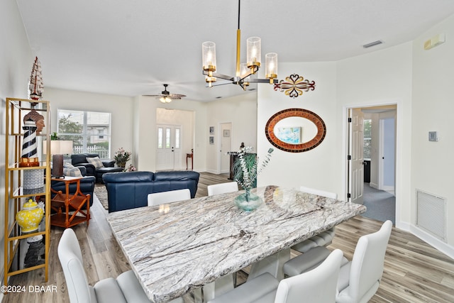 dining room featuring light wood-type flooring and ceiling fan with notable chandelier