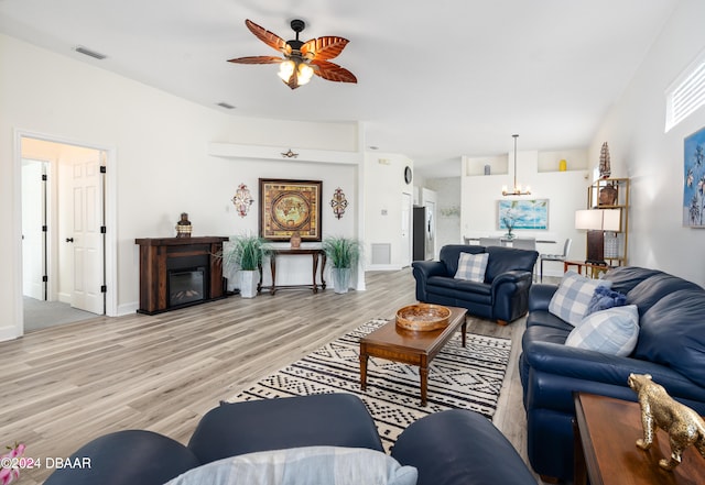 living room with light hardwood / wood-style floors and ceiling fan with notable chandelier