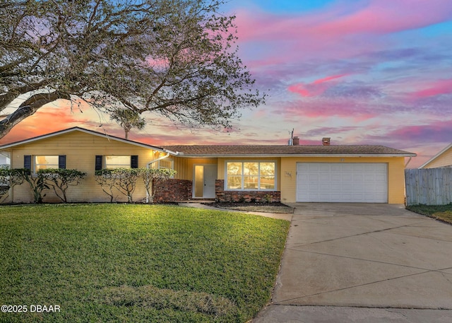 ranch-style house with a garage and a lawn