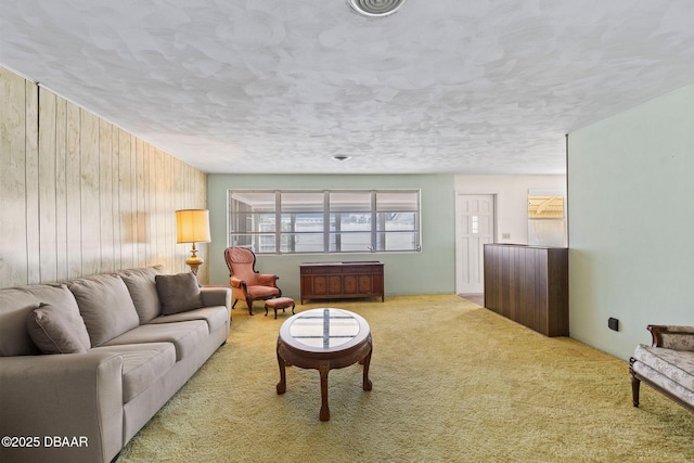 carpeted living room featuring wooden walls and a textured ceiling