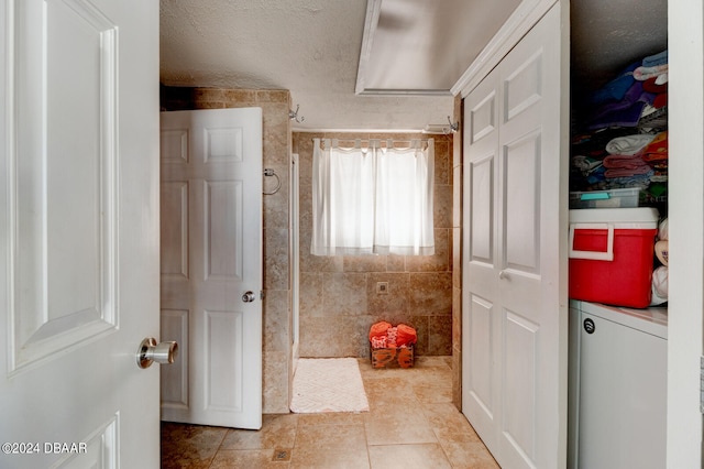 bathroom with tile walls, a textured ceiling, and tile patterned floors