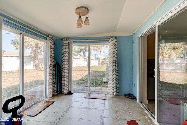 unfurnished dining area with plenty of natural light, light tile patterned floors, and vaulted ceiling