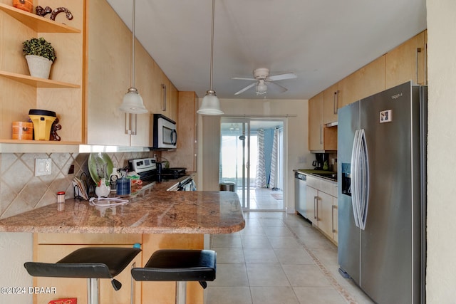 kitchen featuring stainless steel appliances, kitchen peninsula, tasteful backsplash, a breakfast bar area, and pendant lighting