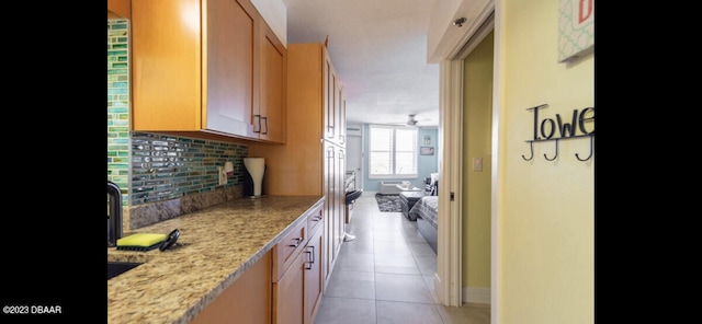 kitchen with ceiling fan, decorative backsplash, light stone counters, and light tile patterned floors