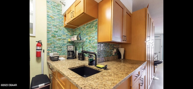 kitchen with sink, light stone counters, and decorative backsplash