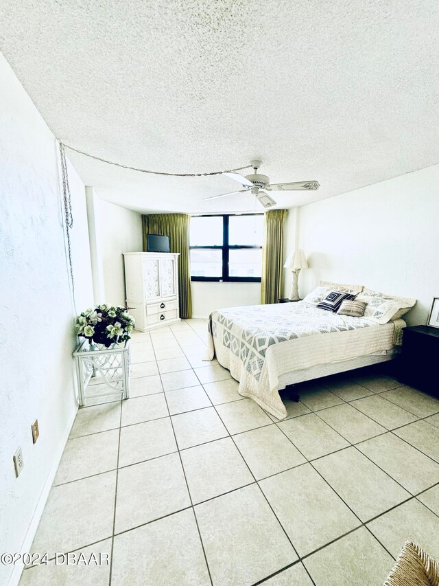 tiled bedroom featuring ceiling fan and a textured ceiling