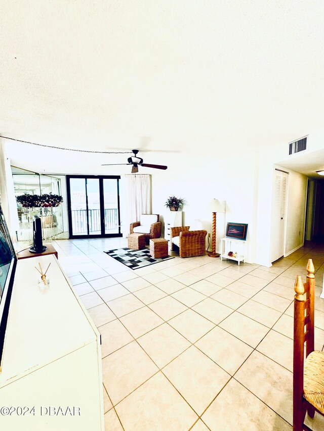 unfurnished living room featuring expansive windows, ceiling fan, and light tile patterned floors