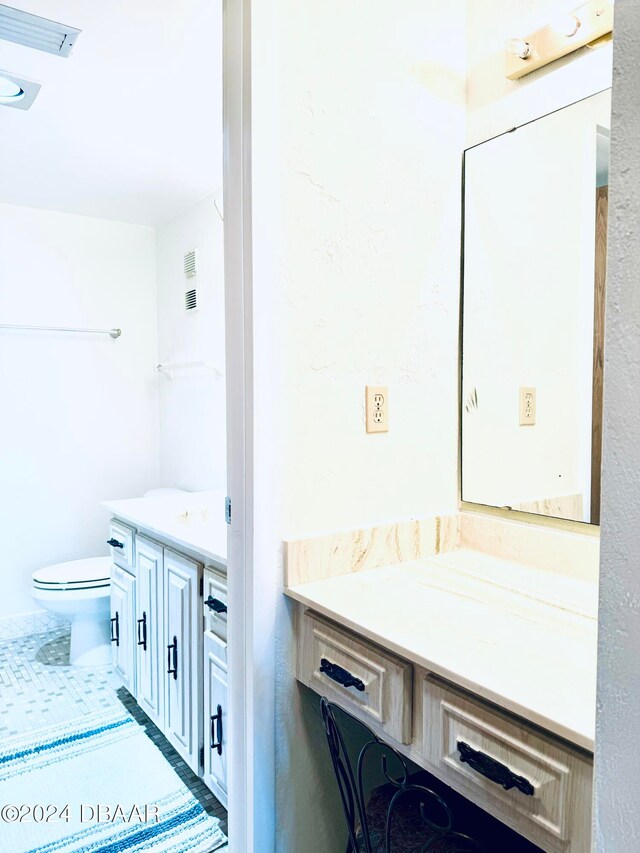 bathroom with toilet, vanity, and tile patterned floors