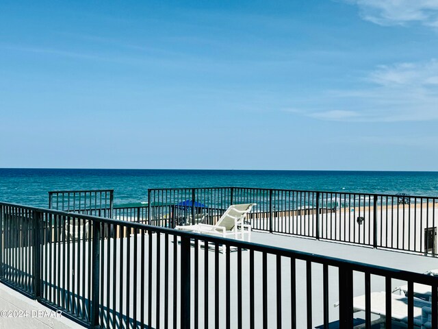 view of patio featuring a balcony, a beach view, and a water view