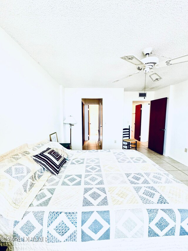 bedroom featuring a textured ceiling, ceiling fan, and light tile patterned floors